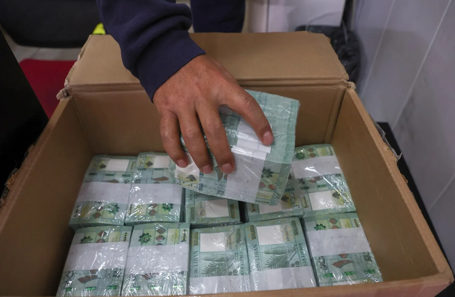 A money exchange vendor holds stacks of Lebanese pound banknotes at a shop in Beirut, Lebanon January 19, 2023. (Reuters)