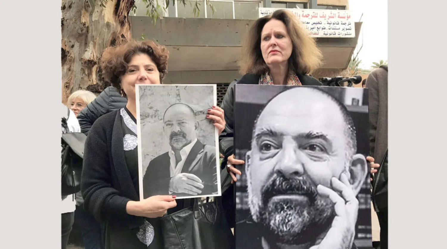 شقيقة لقمان سليم (إلى اليسار) وزوجته ترفعان صوره في منزل العائلة في الضاحية الجنوبية لبيروت (موقع مؤسسة لقمان سليم)