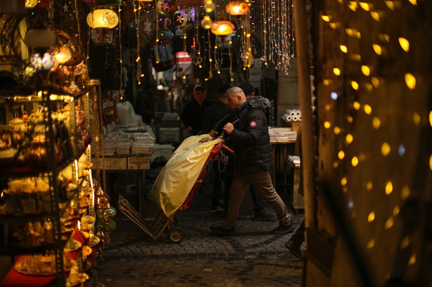 A man carries goods in a trolley along an alley in a street market in Eminonu commercial area in Istanbul, Turkey, Tuesday, Jan. 31, 2023. (AP)