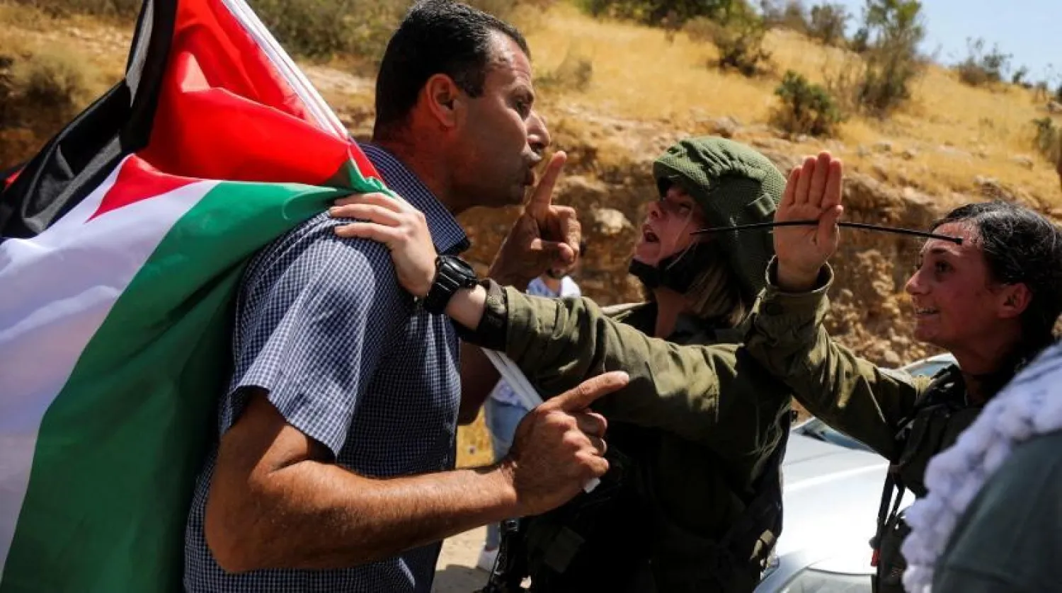 Israeli soldiers argue with a demonstrator holding a Palestinian flag during a protest against Israeli settlements in Jordan Valley in the Israeli-occupied West Bank June 6, 2022. Picture taken June 6, 2022. (Reuters)
