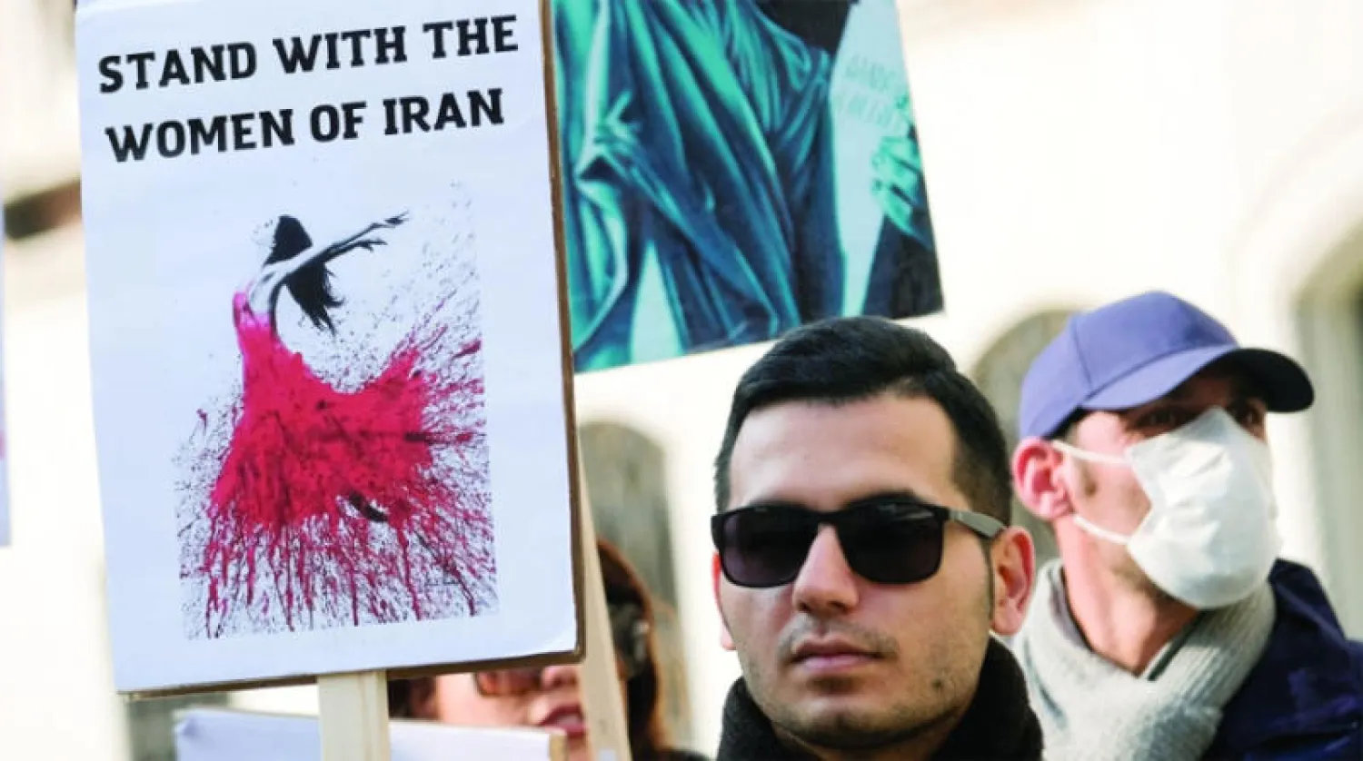 شاب يحمل لافتة كتب عليها «قف مع نساء إيران» في البندقية الجمعة الماضية (رويترز)