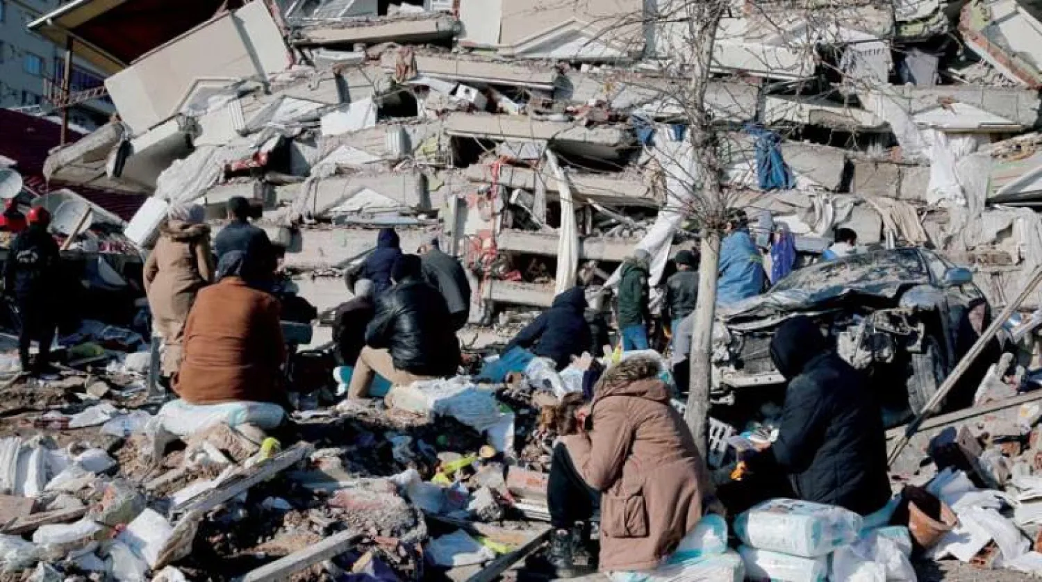 مواطنون أمام مبنى منهار في كهرمان ماراش بتركيا أمس (رويترز)