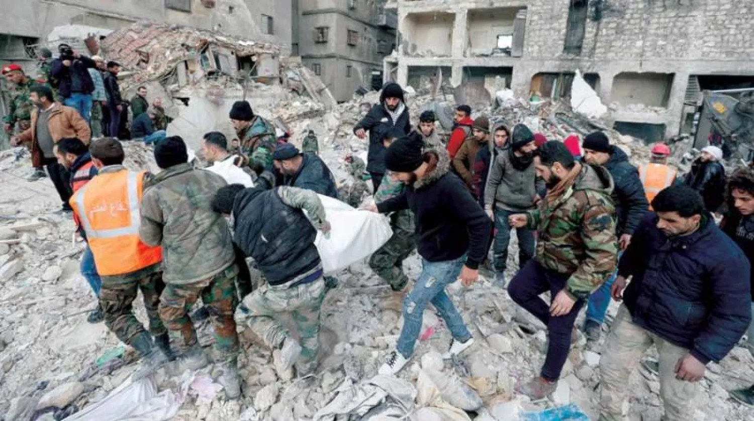 مسعفون ينقلون جثة بين أنقاض مبنى في مدينة حلب أول من أمس (أ.ب)