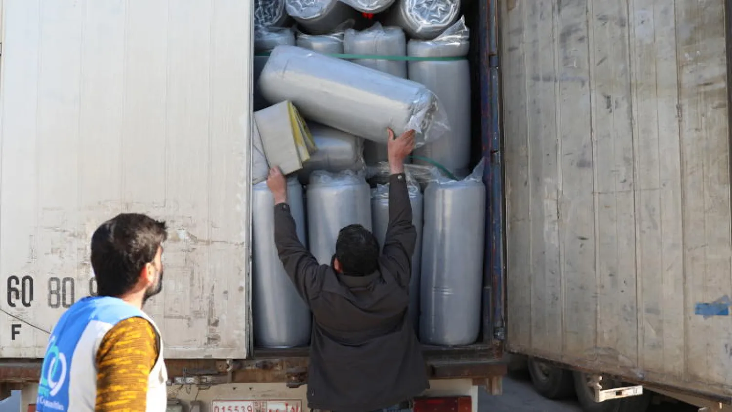 مسؤولون يفحصون الشاحنات التي تحمل مواد إغاثية مرسلة من قبل وكالات الأمم المتحدة لمساعدة الضحايا المتضررين من الزلزال بعد عبور معبر باب الهوى الحدودي بمحافظة إدلب (إ.ب.أ)