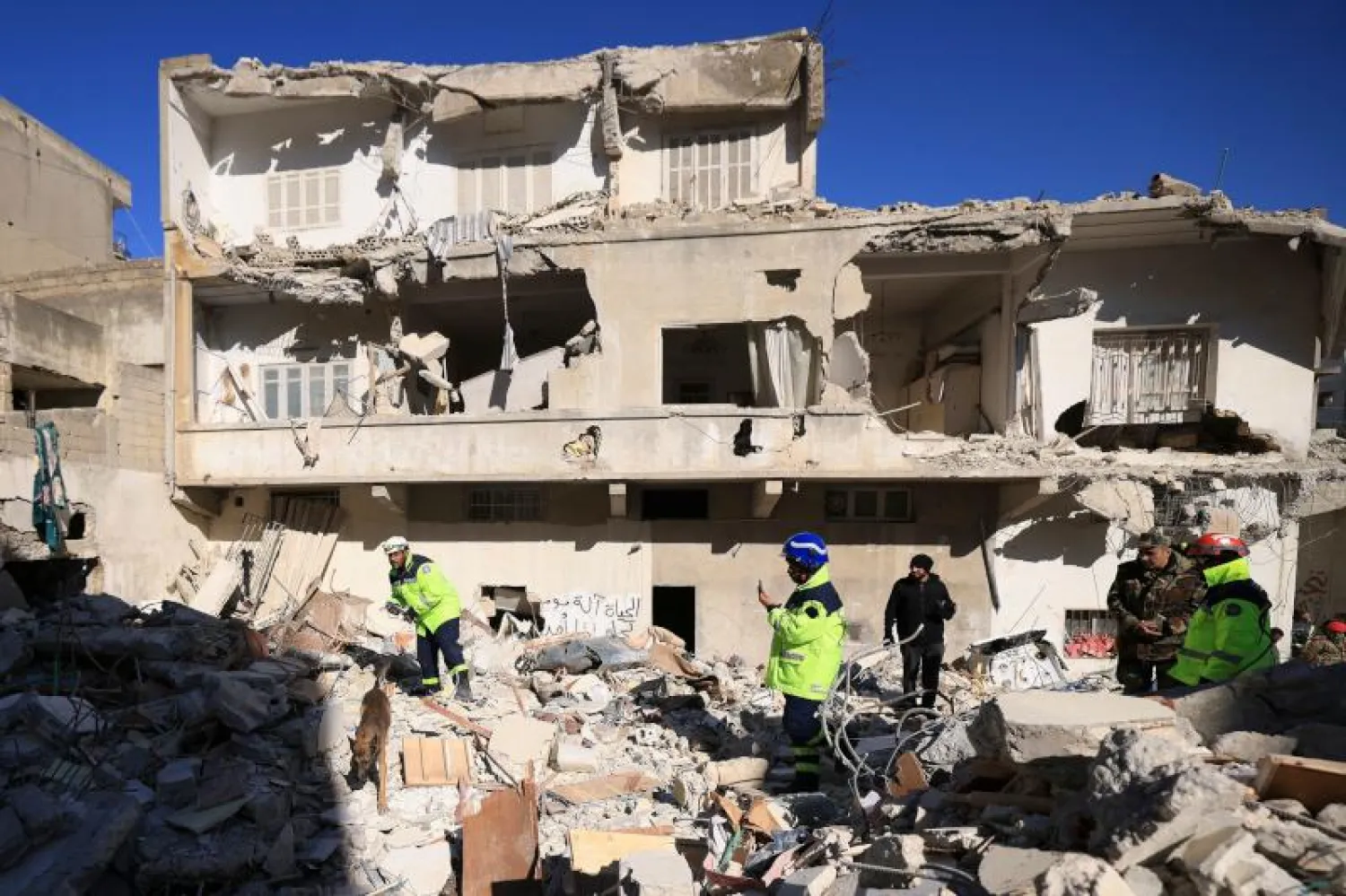 منقذ يبحث عن ضحايا بمساعدة كلب وسط أنقاض مبنى منهار في بلدة جبلة بمحافظة اللاذقية شمال غربي العاصمة السورية (أ.ف.ب)