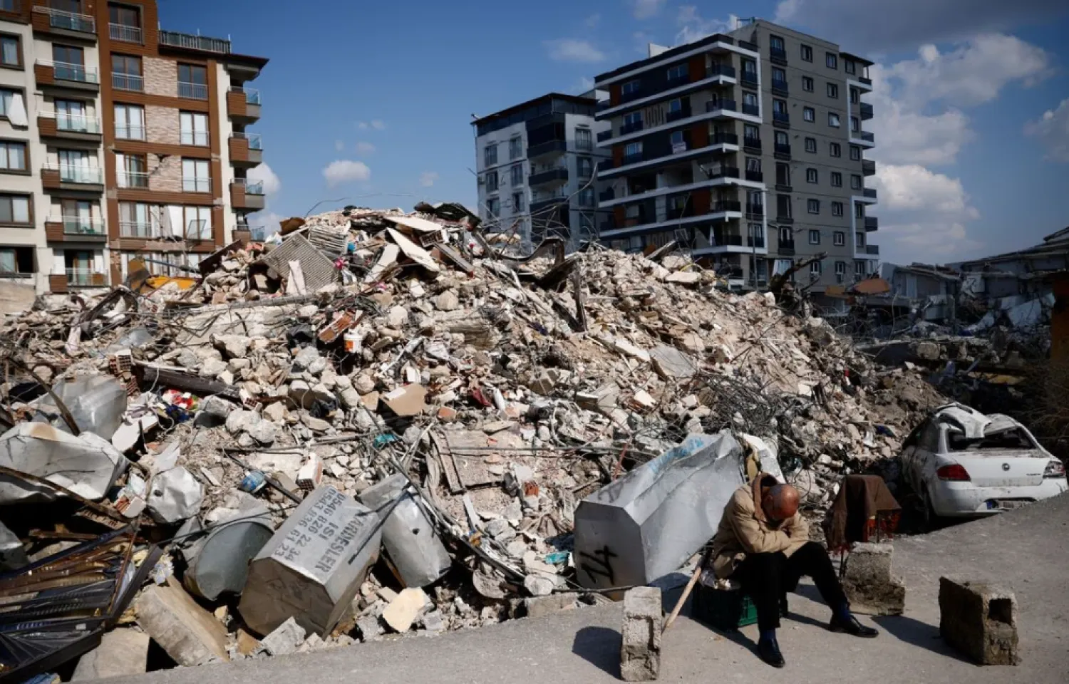 A man sits next to rubble at the site of a collapsed building in the aftermath of a deadly earthquake in Antakya, Turkiye February 10, 2023. REUTERS/Guglielmo Mangiapane
