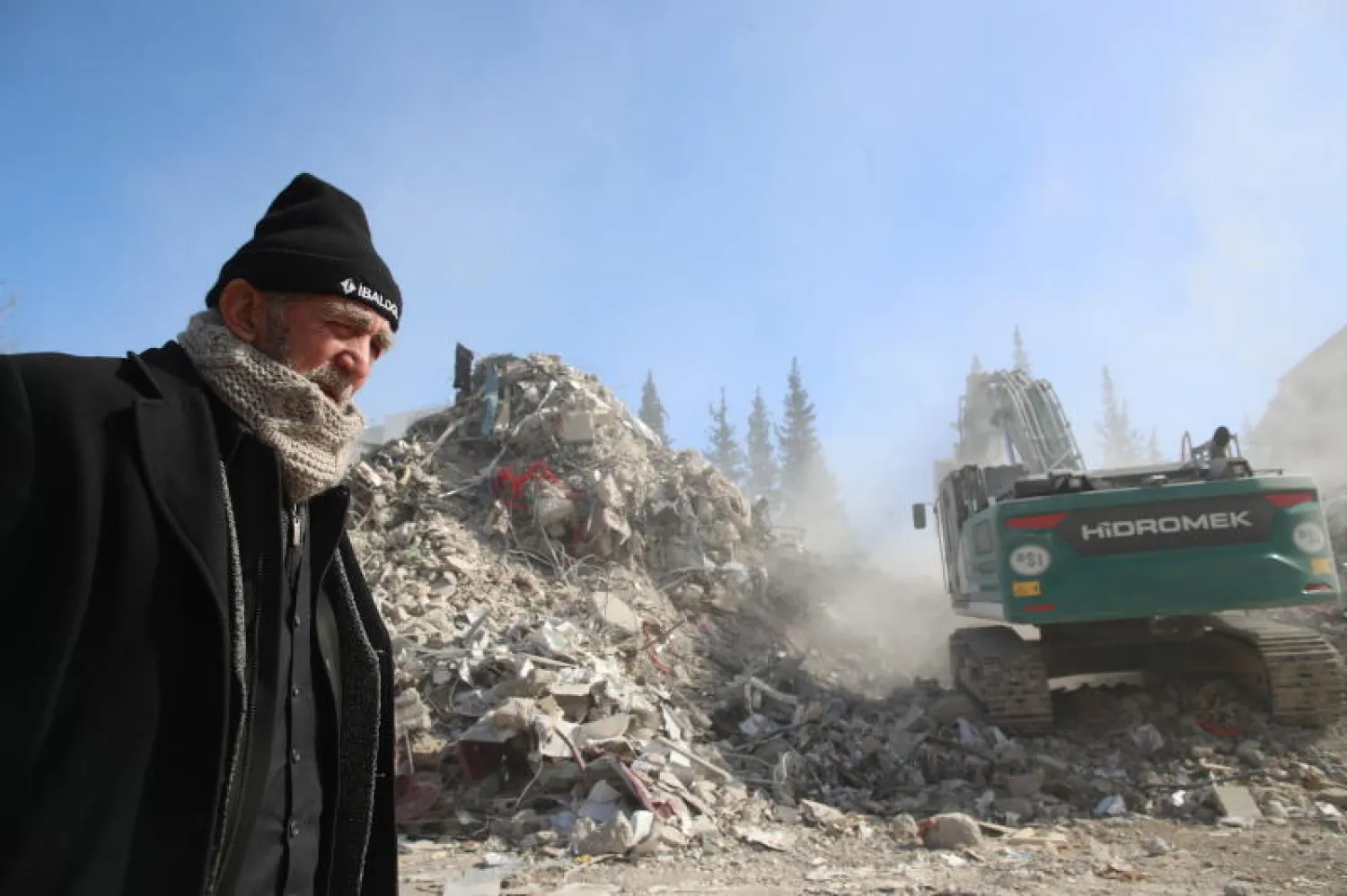 رجل يسير بجوار أنقاض مبنى مهدم بفعل الزلزال في منطقة كهرمان مرعش (إ.ب.أ)