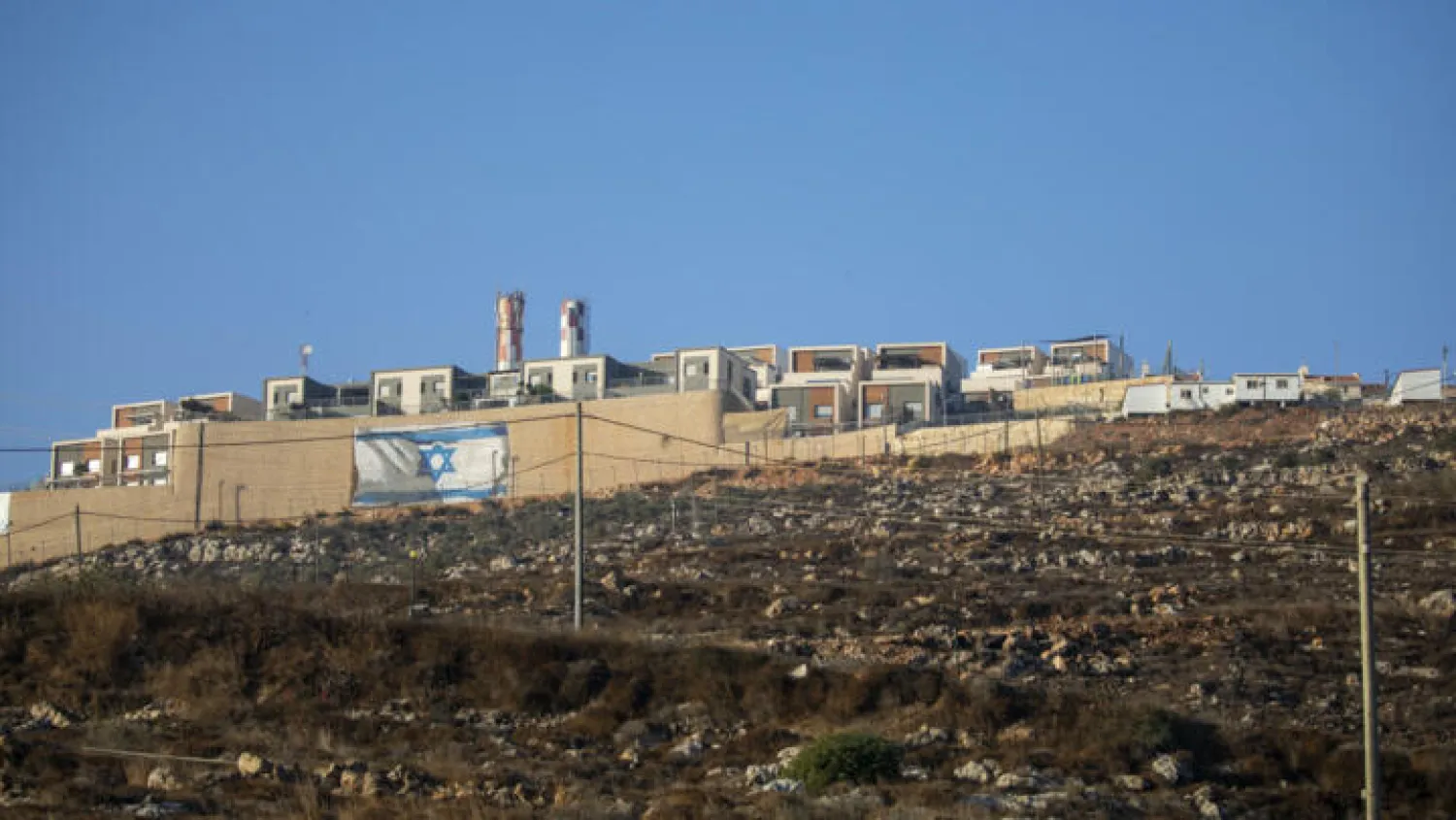 File photo: An Israeli flag is painted on the surrounding wall of the West Bank Jewish settlement of Migdalim near the Palestinian town of Nablus, Monday, Oct. 25, 2021. © Ariel Schalit, AP
