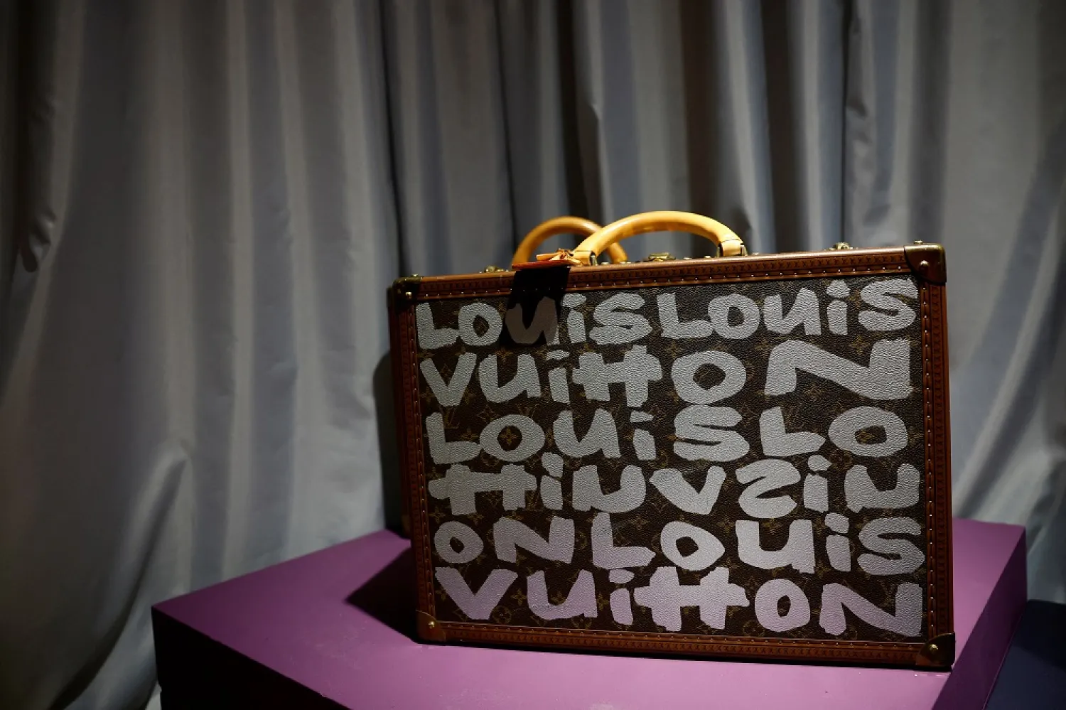 A Louis Vuitton limited edition graffiti monogram canvas hardsided briefcases by Stephen Sprouse is displayed during the exhibition of the Couture collection of late fashion icon Andre Leon Talley in the showroom of Christie's auction house in Paris, France, January 24, 2023. (Reuters)