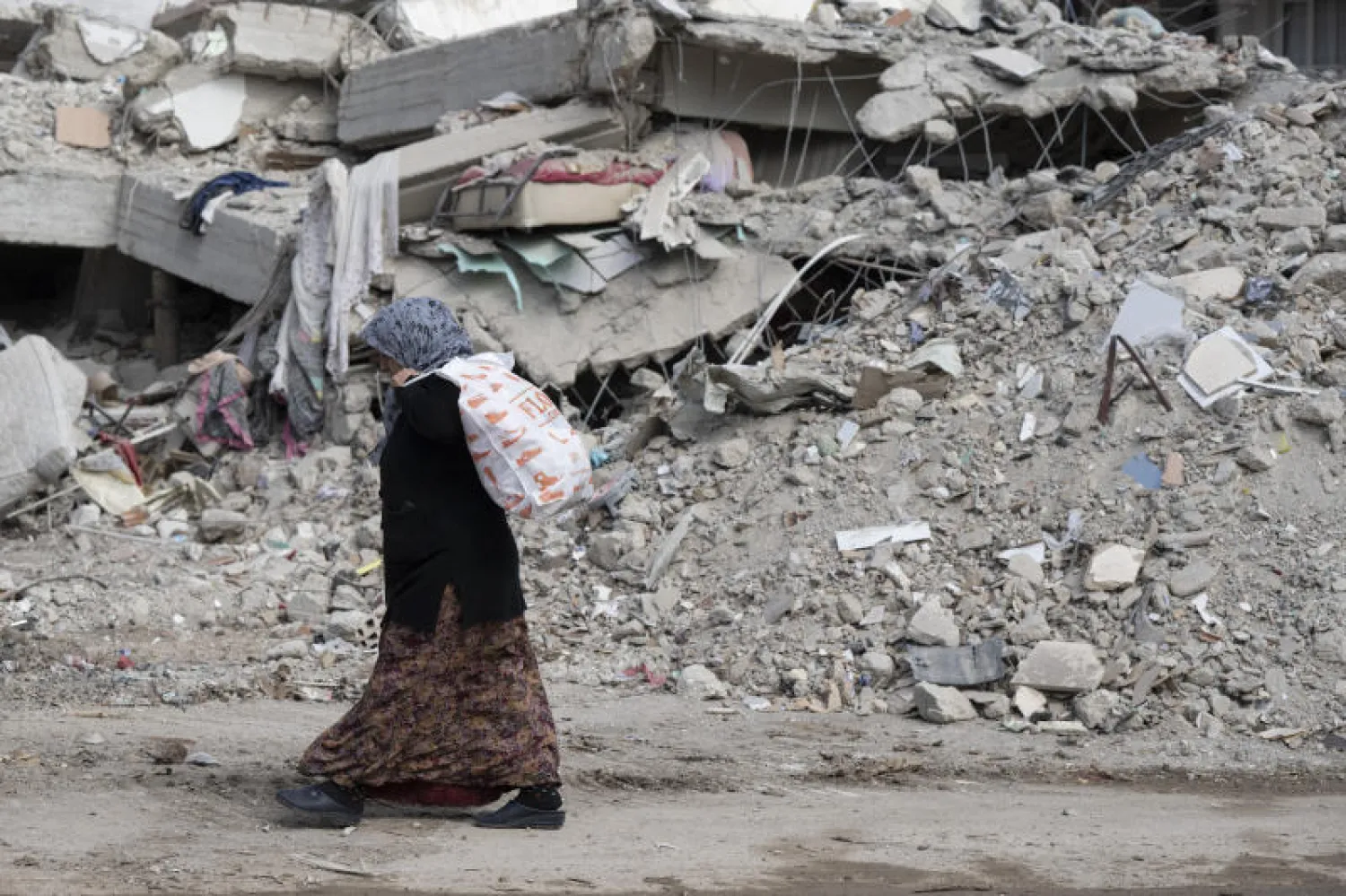 امرأة تعبر بين الركام (د.ب.أ)