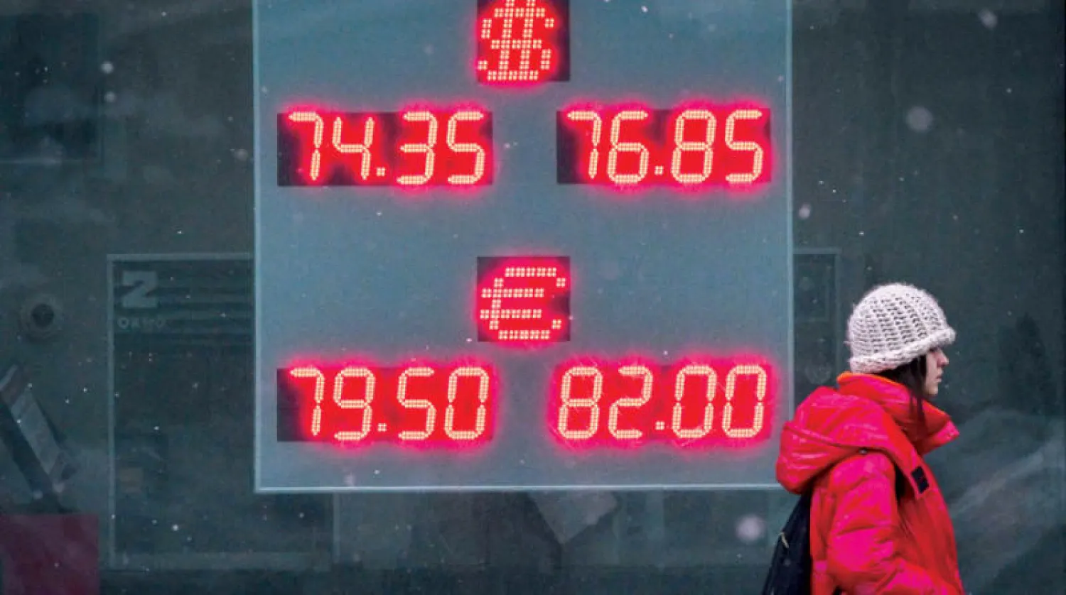 سيدة تمر أمام شاشة تعرض سعر الروبل الروسي مقابل الدولار واليورو في العاصمة موسكو (أ.ف.ب)