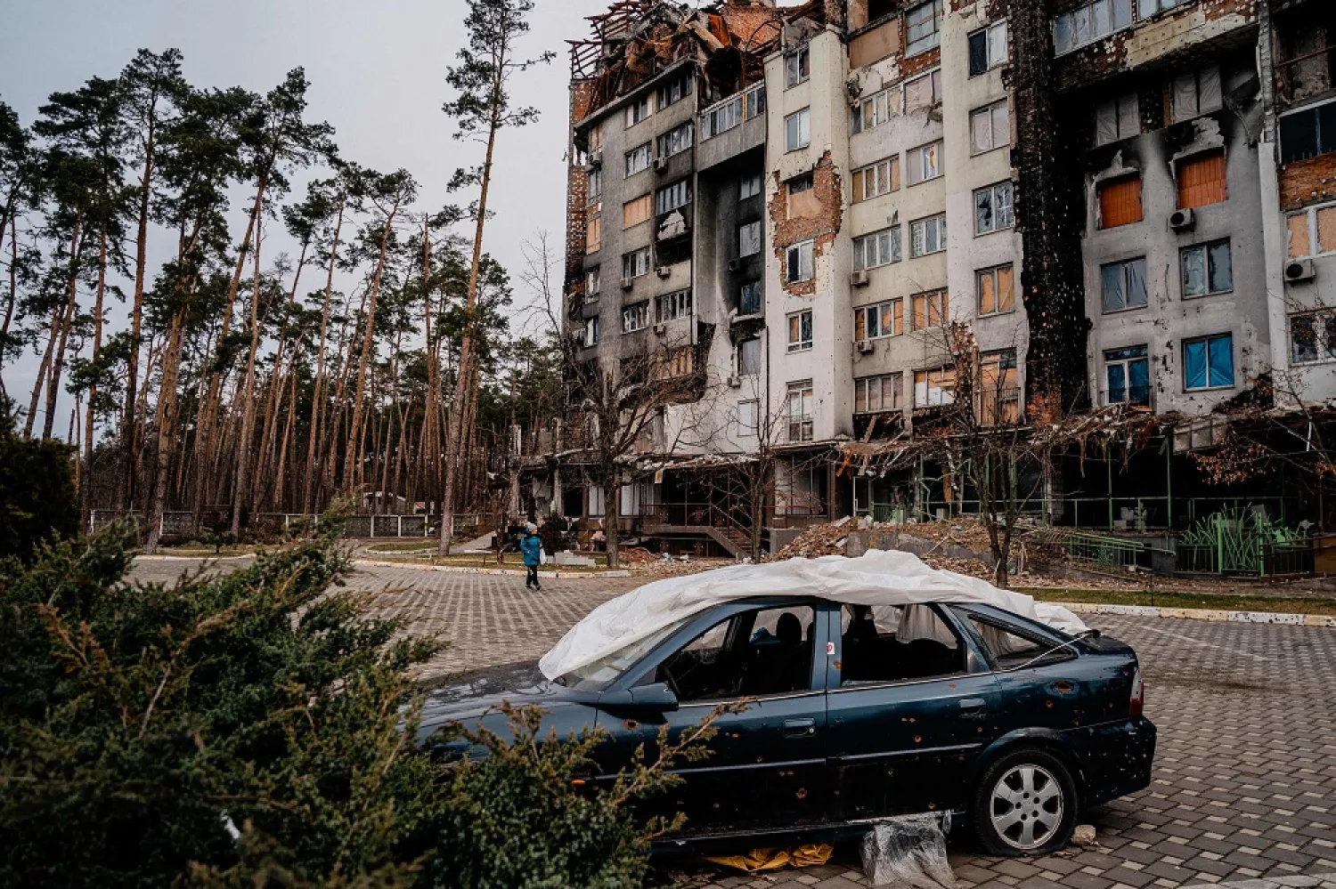 A woman walks past a residential building at the Irpinsky Lipky residential complex, which was heavily damaged during fighting between Russian and Ukrainian troops in the town of Irpin, near Kyiv on February 16, 2023. (AFP)

