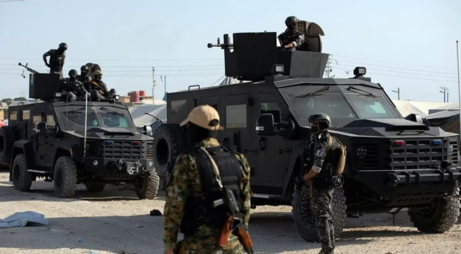 A Syrian Democratic Forces (SDF) fighter stands near Kurdish internal security special forces during a security operation in al-Hol camp which holds displaced people and families of Islamic State fighters, in Hasaka governorate, in northeast Syria August 26, 2022. REUTERS/Orhan Qereman