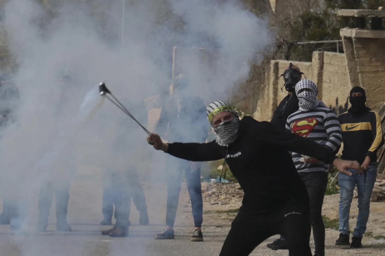 متظاهر فلسطيني يلقي حجارة خلال اشتباكات مع القوات الإسرائيلية في الضفة الغربية المحتلة (أ.ف.ب)