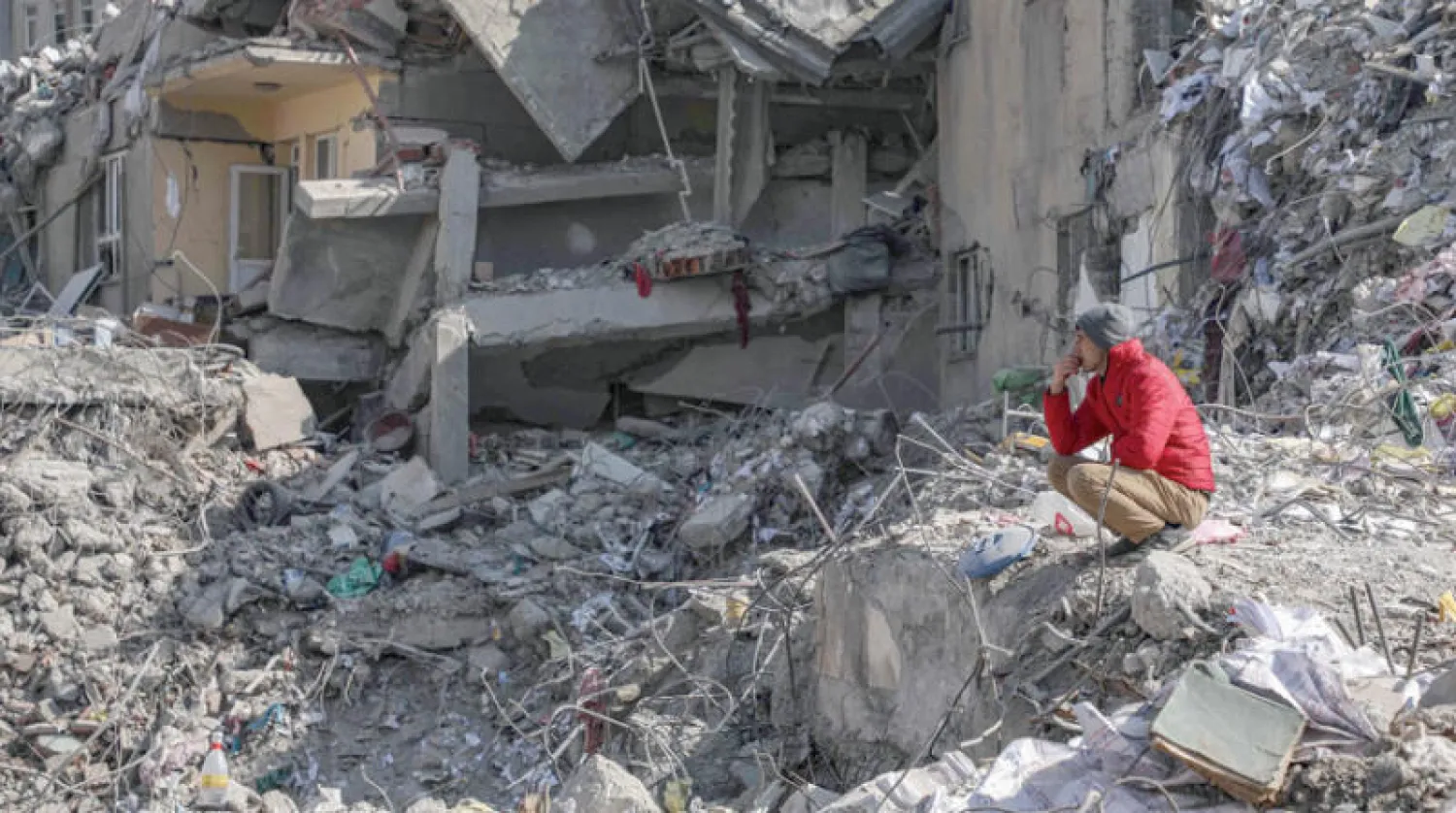 ناجٍ على أنقاض مبنى كان يحوي مسكنه في كهرمان ماراش (أ.ف.ب)