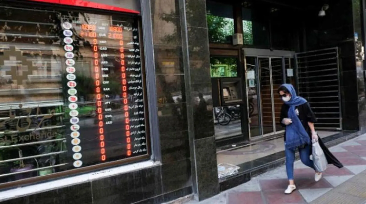 سيدة إيرانية تمر أمام محل صرافة في طهران (رويترز)