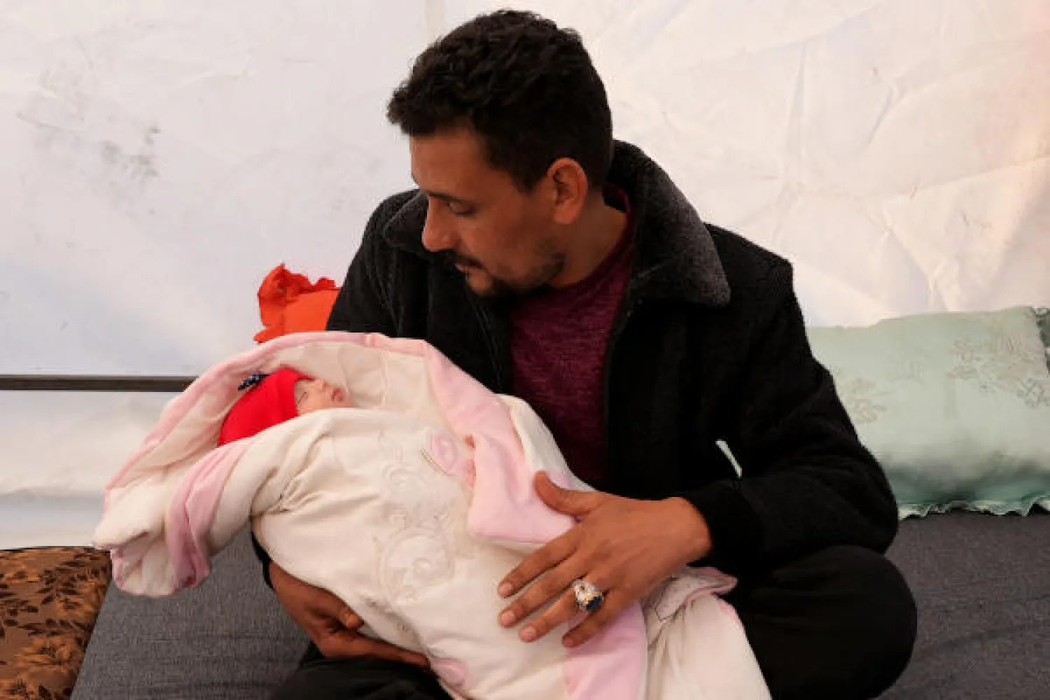 الطفلة عفراء يحملها زوج عمّتها خليل شامي السوادي (أ.ف.ب)