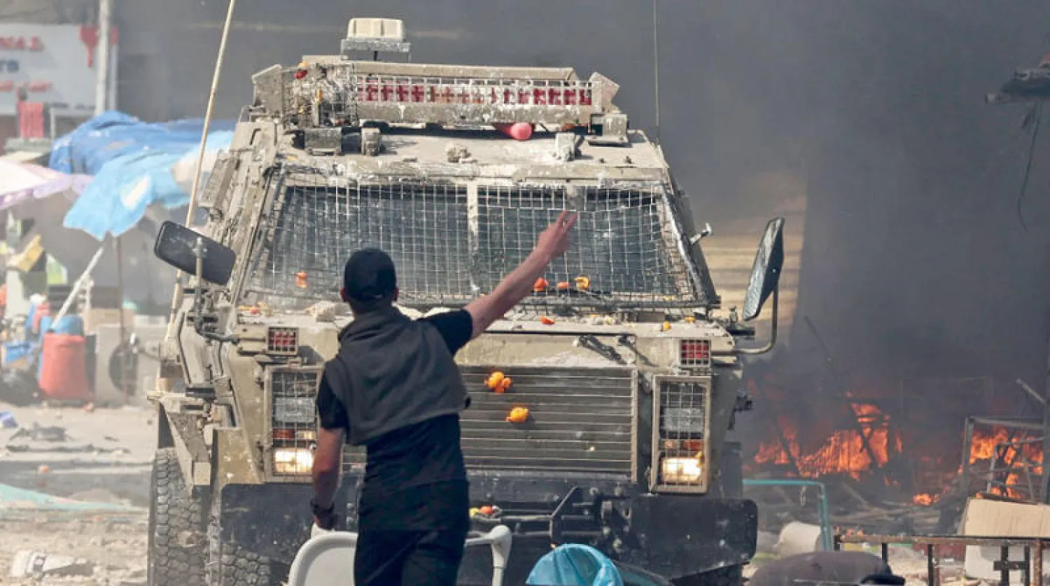 شاب فلسطيني في مواجهة عربة عسكرية إسرائيلية خلال الاشتباكات في نابلس أمس (أ.ف.ب)