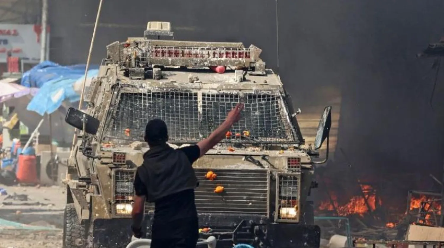 A Palestinian faces an Israeli military vehicle during a raid on the occupied-West Bank city of Nablus, on February 22, 2023. - Israeli troops killed at least 10 Palestinians in a raid on Nablus, while more than 80 suffered gunshot wounds, the Palestinian health ministry said. (Photo by Zain Jaafar / AFP)