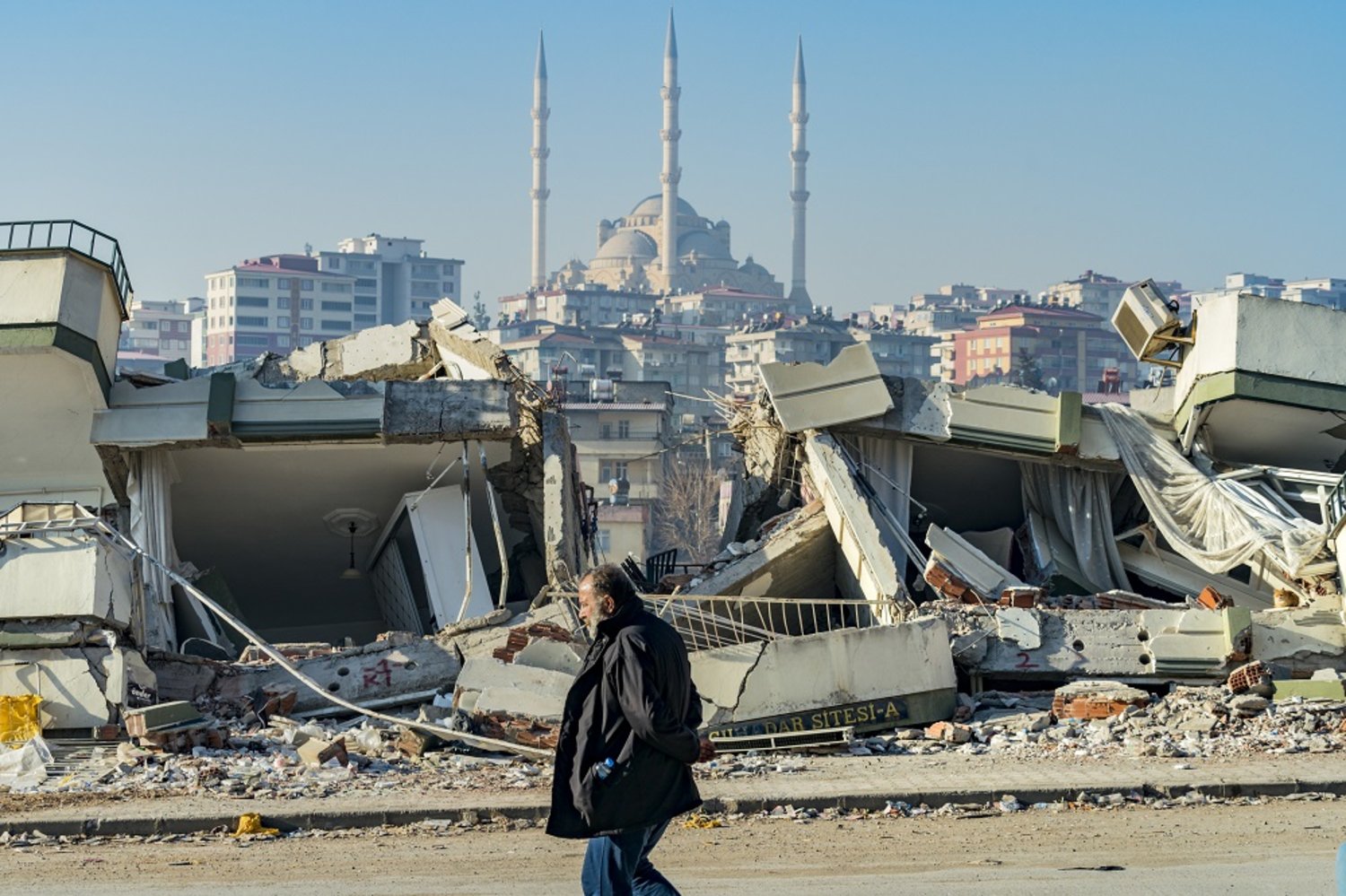 18 February 2023, Türkiye, Kahramanmaras: A man walks past a building that was destroyed by the deadly earthquake that struck the Turkish provinces of Hatay and Kahramanmaras. (dpa)
