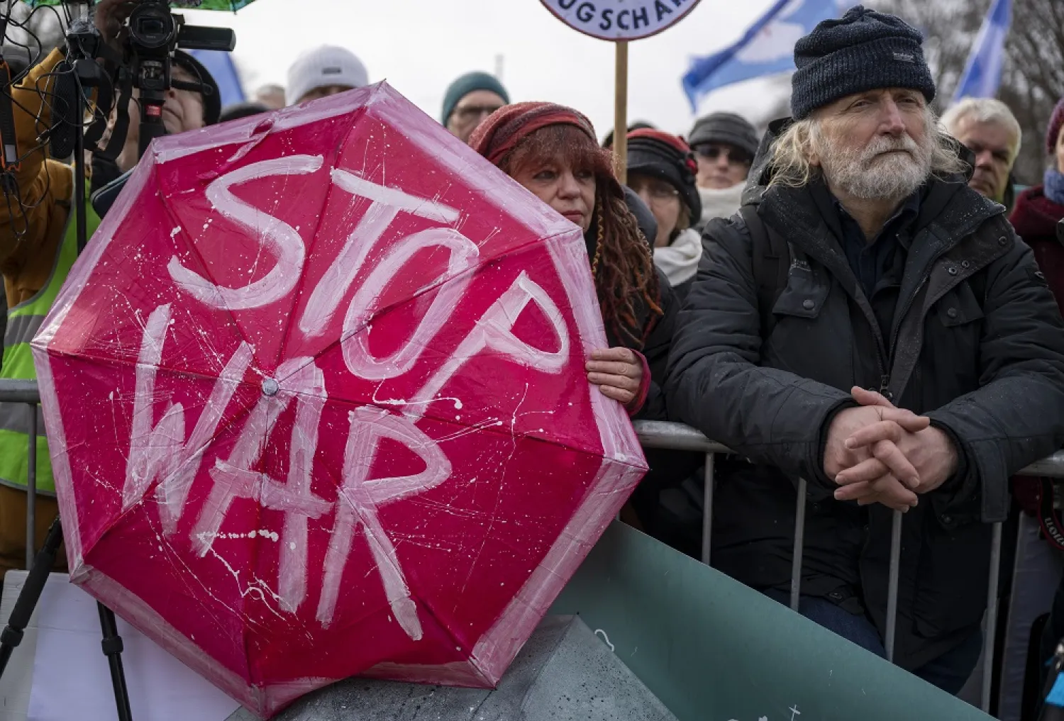 25 February 2023, Berlin: A woman holds an umbrella with the inscription "Stop War" during a rally at the Brandenburg Gate, in favor of negotiations with Russia in the Ukraine war. (dpa)