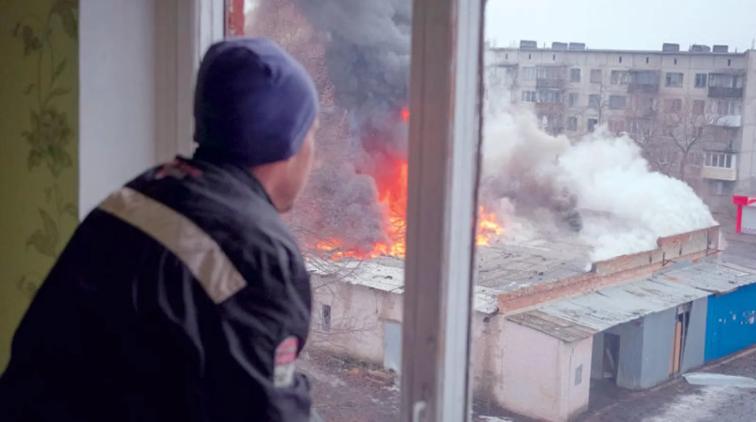 رجل ينظر إلى مبانٍ دمّرها القصف في مدينة شازيف يار بإقليم دونيتسك أمس (رويترز)