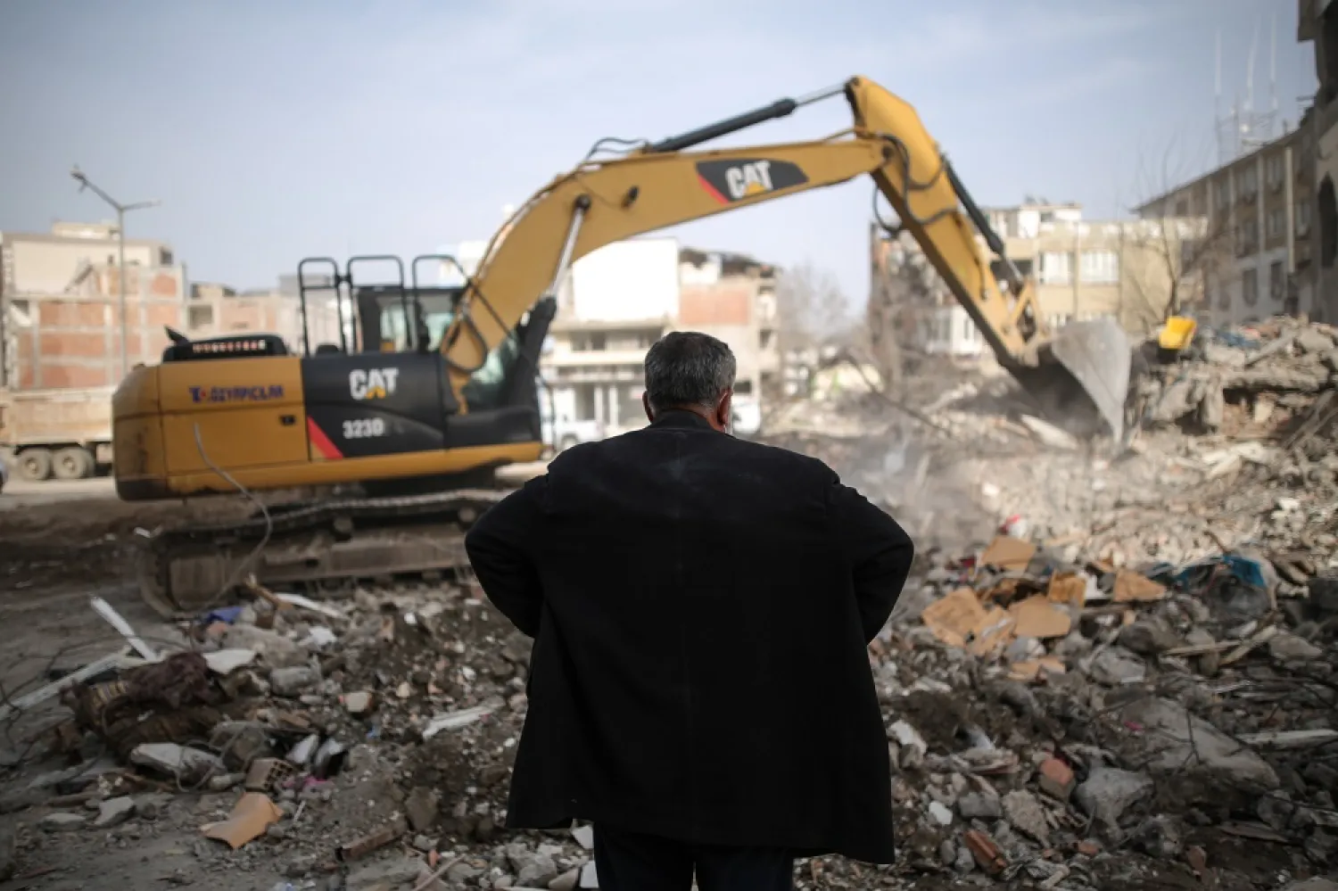 A man stand in front of a collapsed building after a powerful earthquake in Adiyaman, Türkiye, 28 February 2023. (EPA)