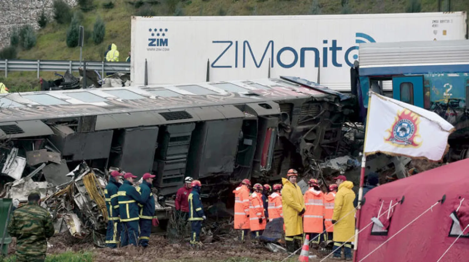 الشرطة وعمال الإنقاذ يتفقدون موقع اصطدام القطارين في لاريسا أمس (أ.ف.ب)