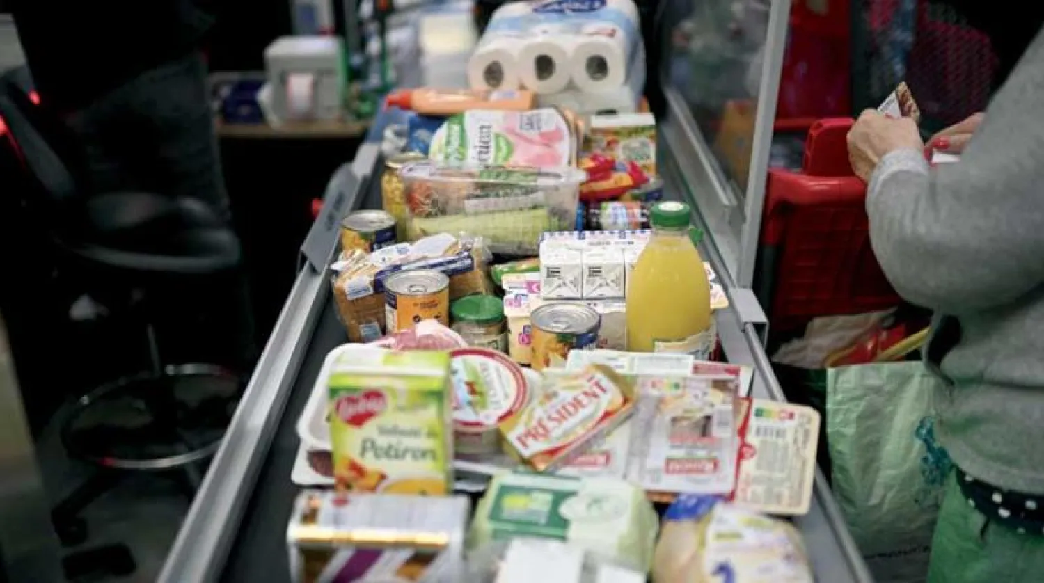 عامل في متجر بقالة بمدينة مارسيليا الفرنسية يقوم بحساب أسعار السلع لأحد الزبائن (أ.ف.ب)