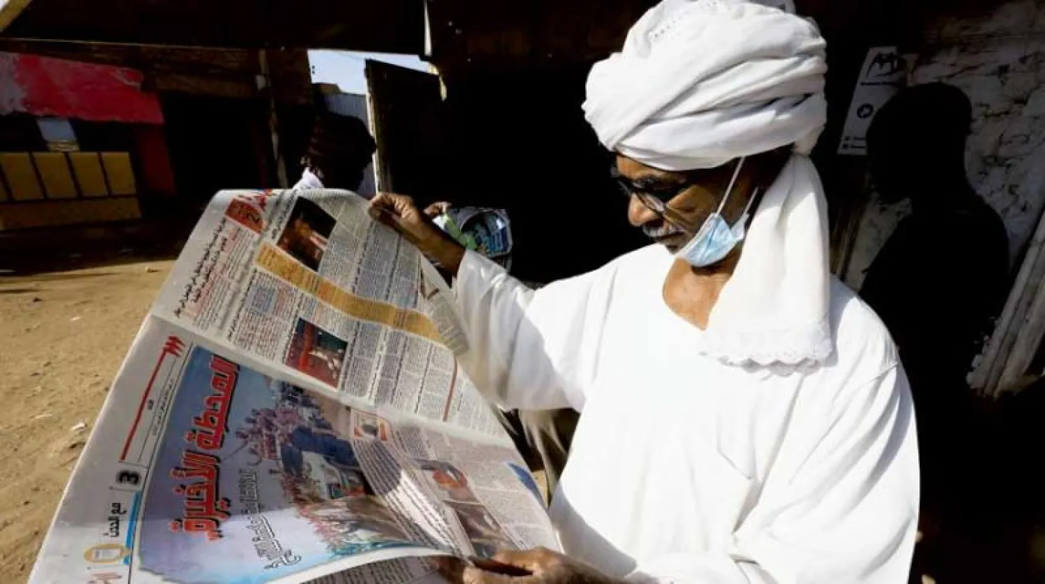 سوداني يقرأ جريدة محلية في مدينة أم درمان (رويترز)