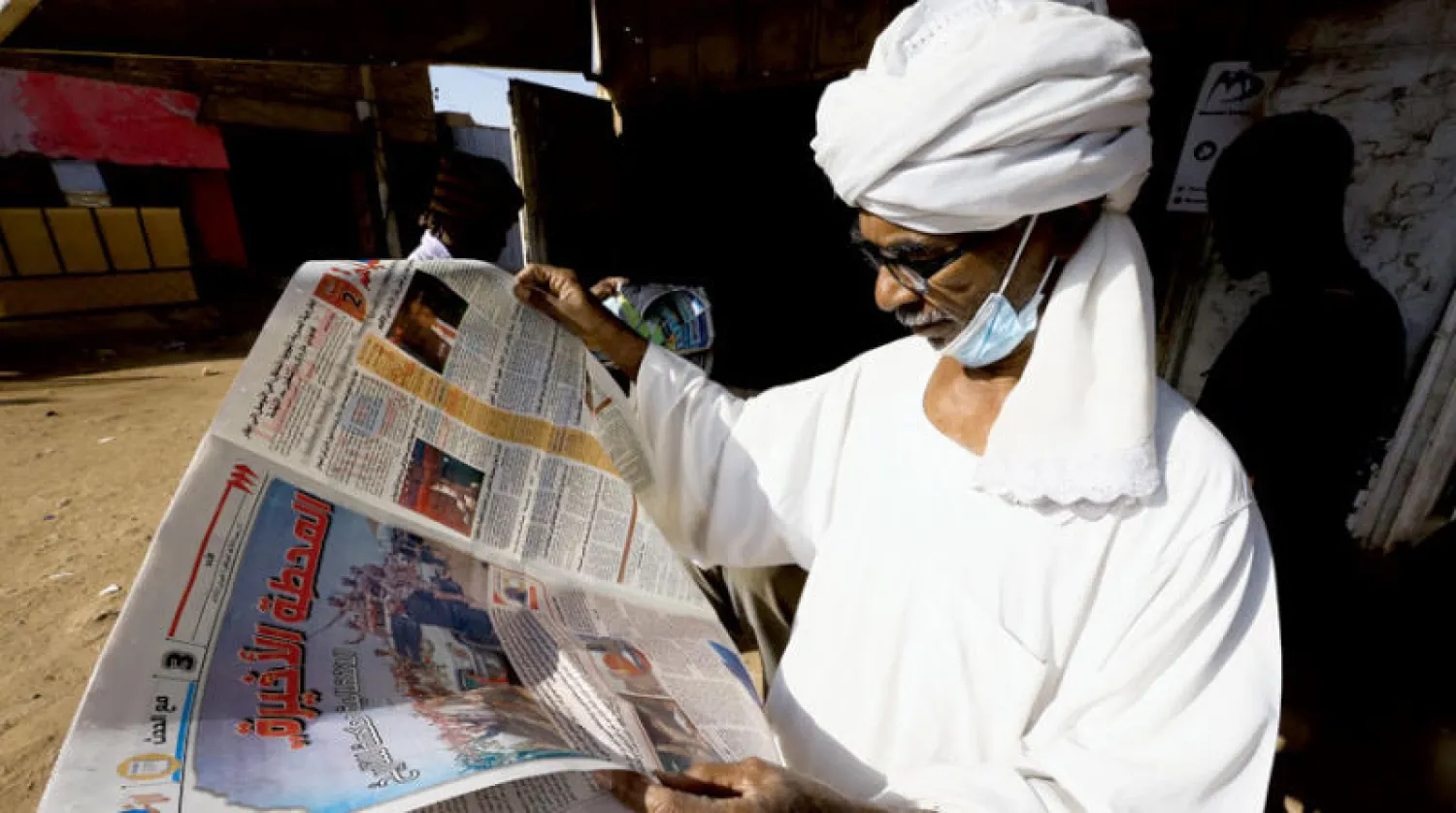سوداني يقرأ جريدة محلية في مدينة أم درمان (رويترز)