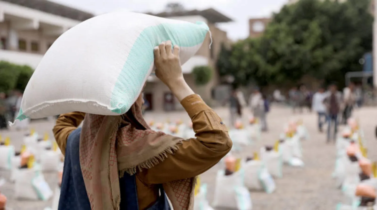 عامل في صنعاء يحمل كيساً من دقيق القمح خلال توزيع مساعدات غذائية من قبل جمعية خيرية محلية (رويترز)