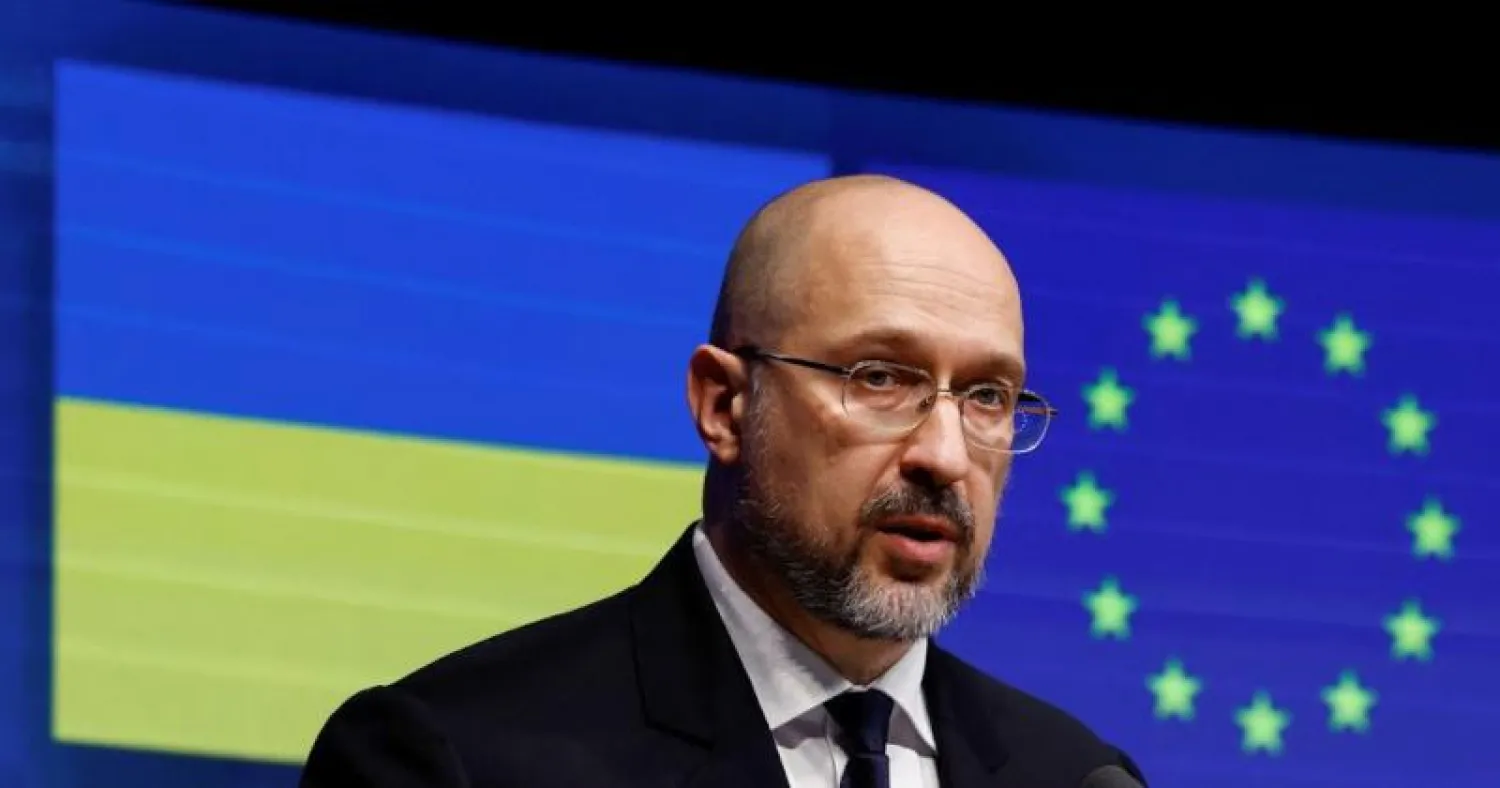 رئيس الوزراء الأوكراني دنيس شميغال... وفي الخلفية علما أوكرانيا والاتحاد الأوروبي (رويترز)