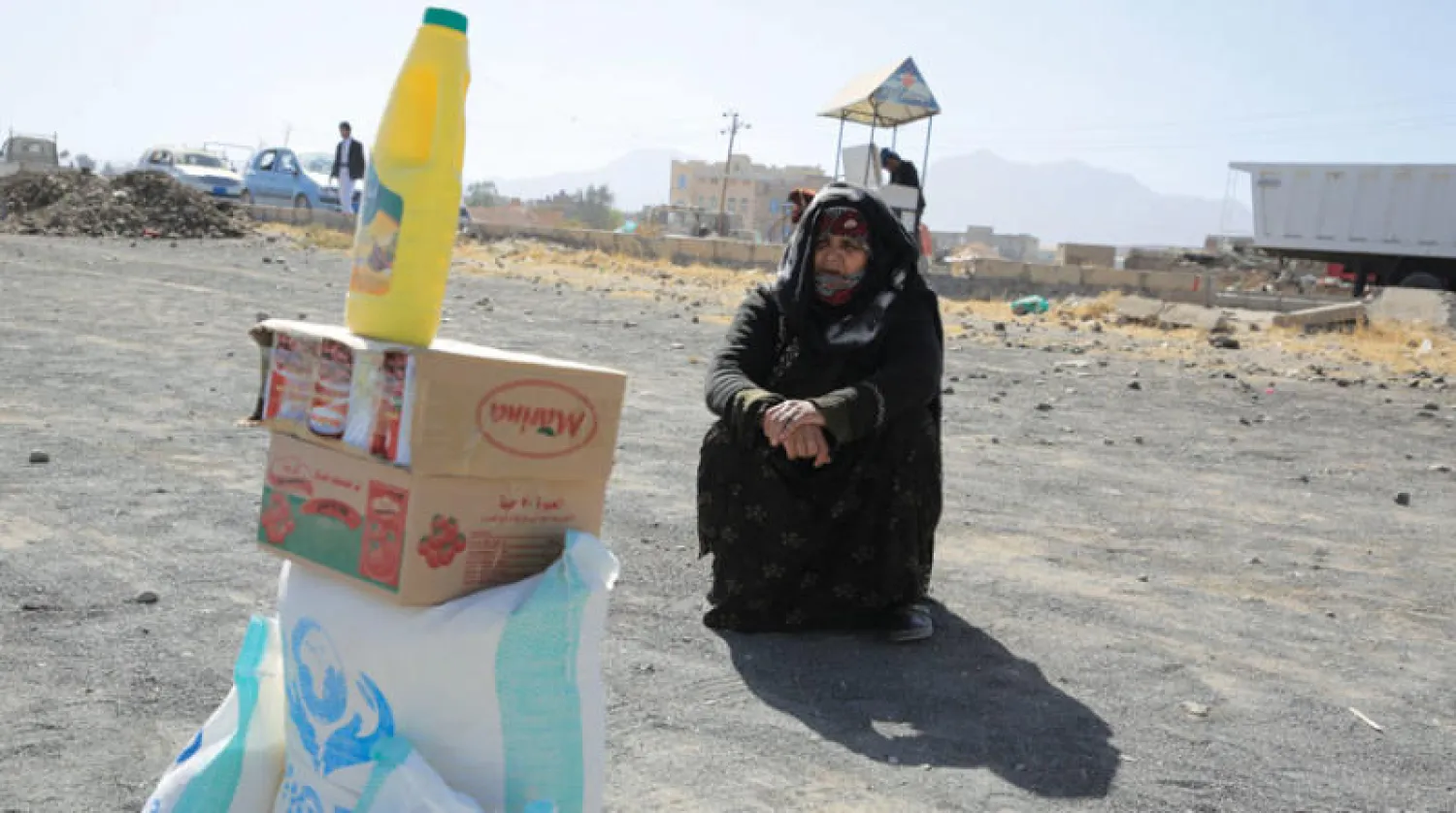 يمنية تجلس بجانب مساعدتها الغذائية وسط انعدام الأمن الغذائي في صنعاء (إ.ب.أ)