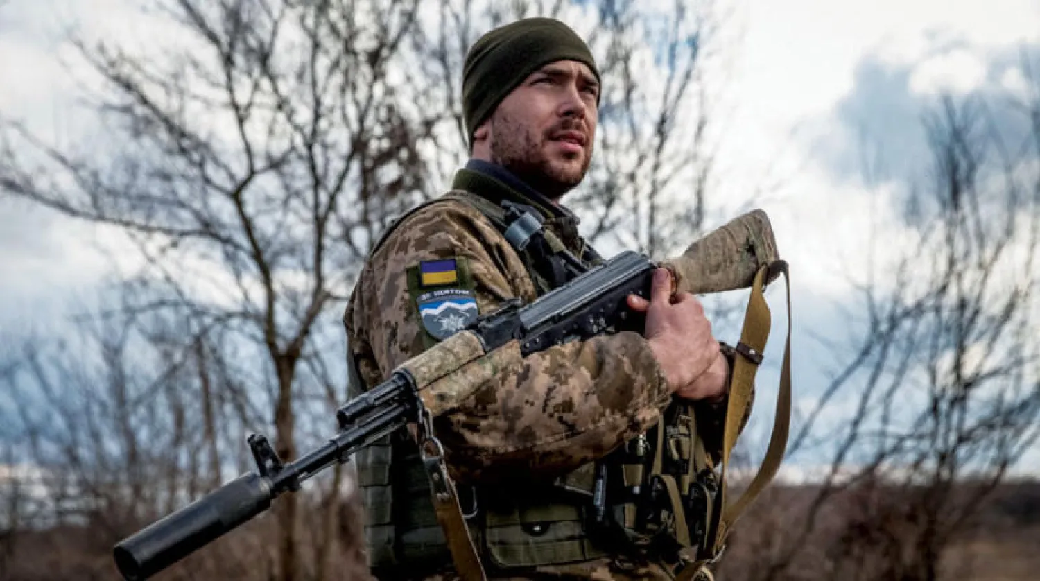 جندي أوكراني مع سلاحه في إحدى جبهات القتال بإقليم دونيتسك (رويترز)