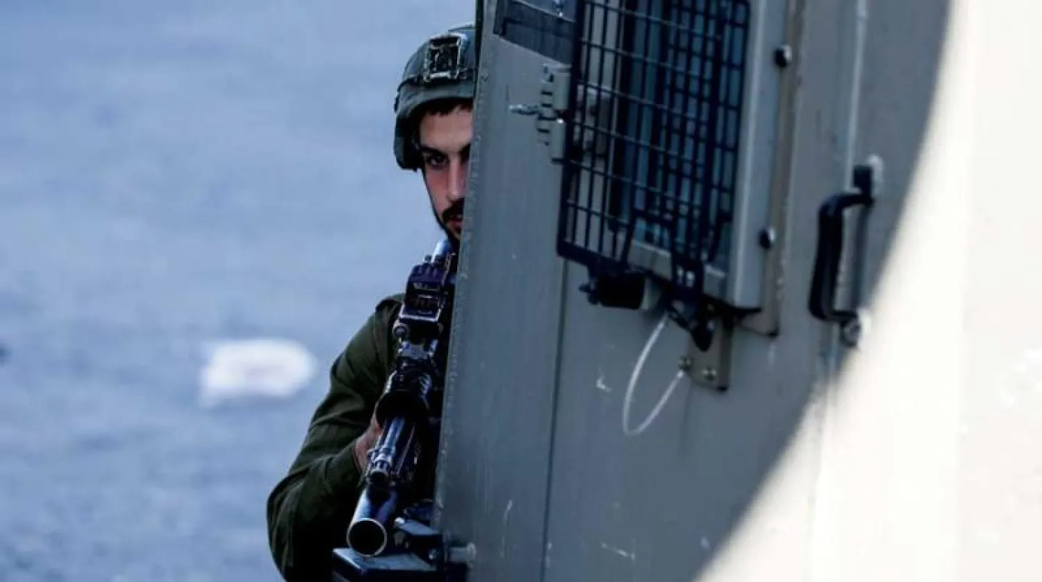 جندي إسرائيلي يحرس موقع تبادل إطلاق نار ليلاً بالقرب من نقطة عسكرية في قرية صرة بالضفة (د.ب.أ)