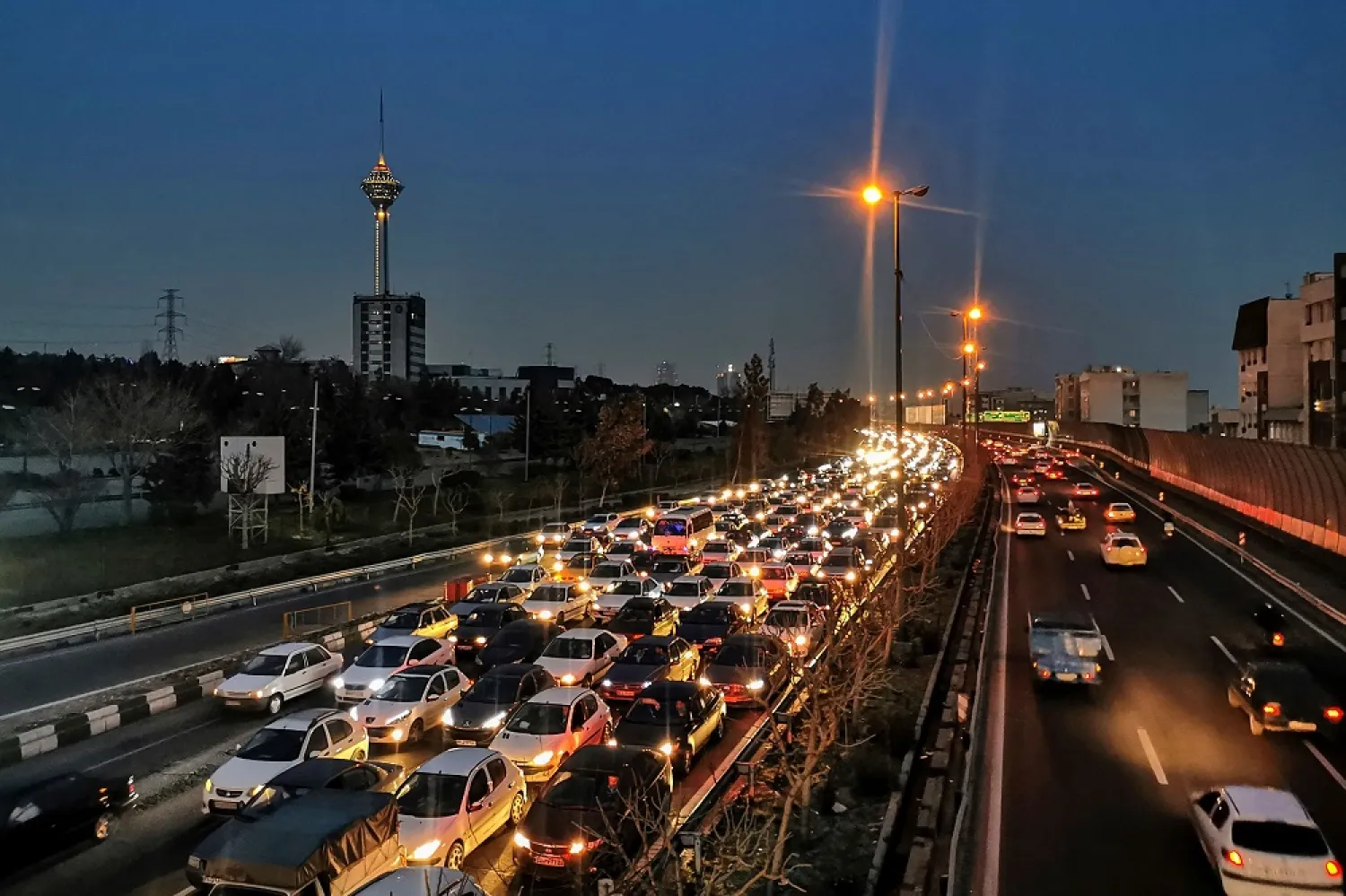 Cars wait in traffic on a highway with a view of the Milad Tower (L) in Tehran, on March 12, 2023. (AFP)