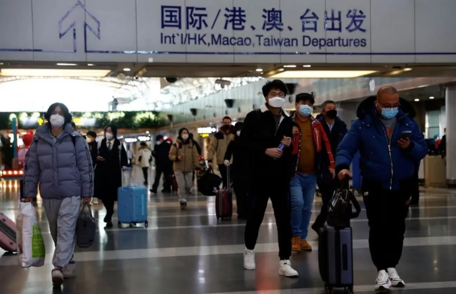 Travelers walk with their luggage at Beijing Capital International Airport, amid the coronavirus disease (COVID-19) outbreak in Beijing, China December 27, 2022. REUTERS/Tingshu Wang