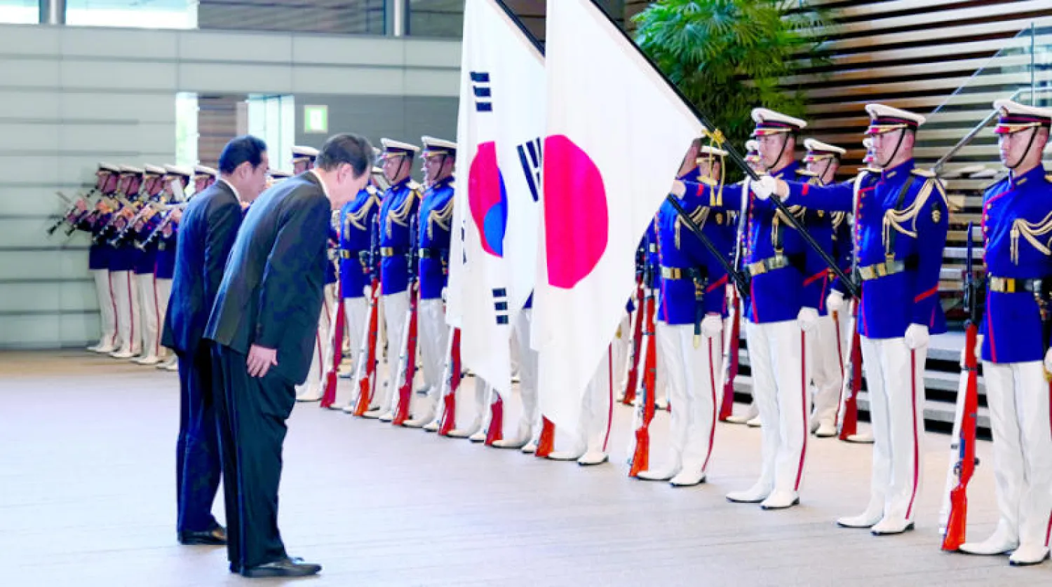 الرئيس الكوري الجنوبي ورئيس الوزراء الياباني ينحنيان أمام علمي البلدين بعد استعراض حرس الشرف في طوكيو أمس (إ.ب.أ)