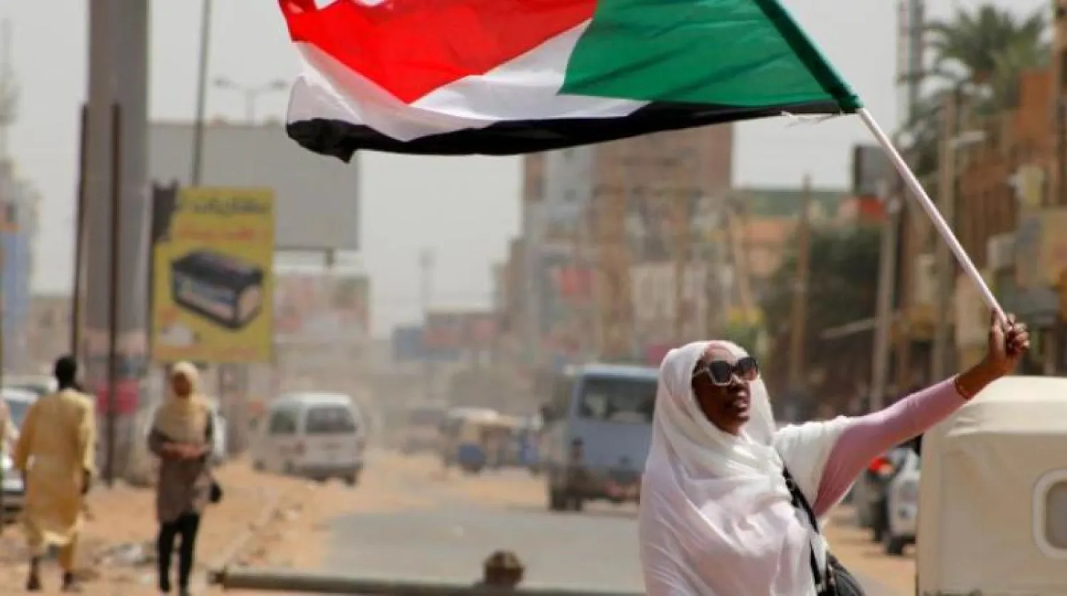 امرأة تحمل العلم السوداني (أ.ف.ب)