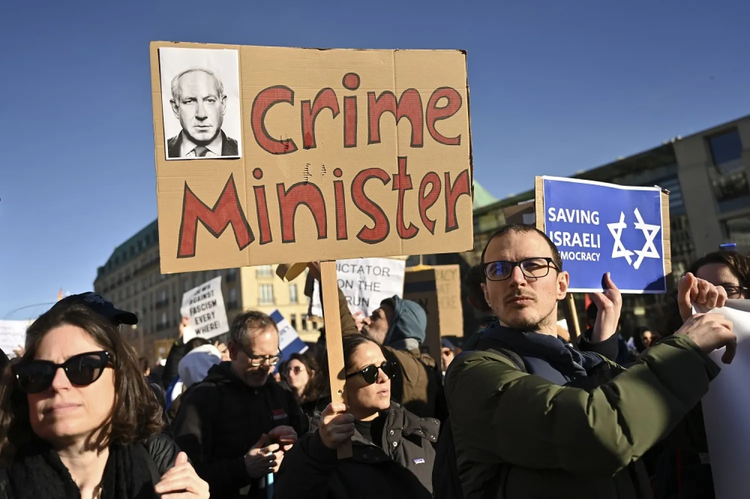 People protest with a sign, reading "crime minister" at a demonstration at the Brandenburg Gate in Berlin against the judicial reform of Israel's Prime Minister Benjamin Netanyahu who is on a visit in Berlin, Germany, Thursday, March 16, 2023. (AP)