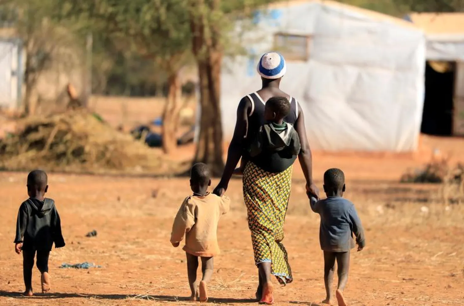 FILE PHOTO: A woman who fled from attacks of armed militants in the Sahel region walks with her children at a camp for internally displaced people (IDPs) in Kaya, Burkina Faso November 23, 2020. Picture taken November 23, 2020. REUTERS/Zohra Bensemra