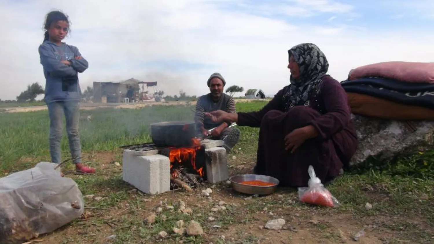 ربة أسرة تطهو الطعام على النار في مركز إيواء بمدينة جسر الشغور (الشرق الأوسط)