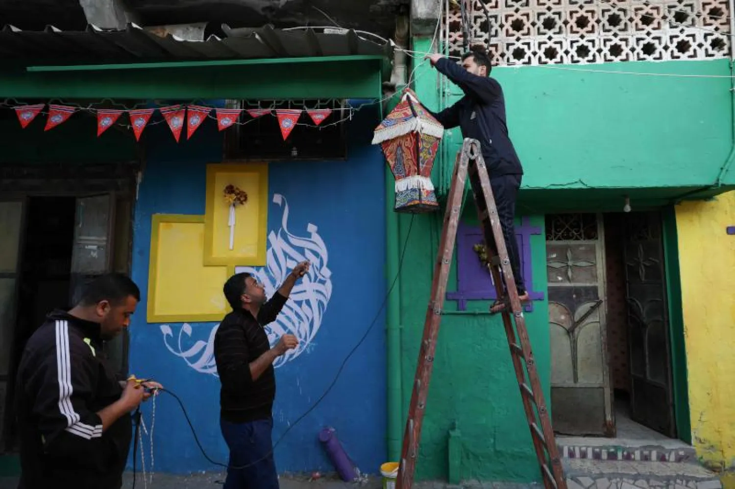 تعليق فانوس رمضان على جدار مطلي بألوان زاهية من فنان فلسطيني في حي الزيتون بمدينة غزة (أ.ف.ب)
