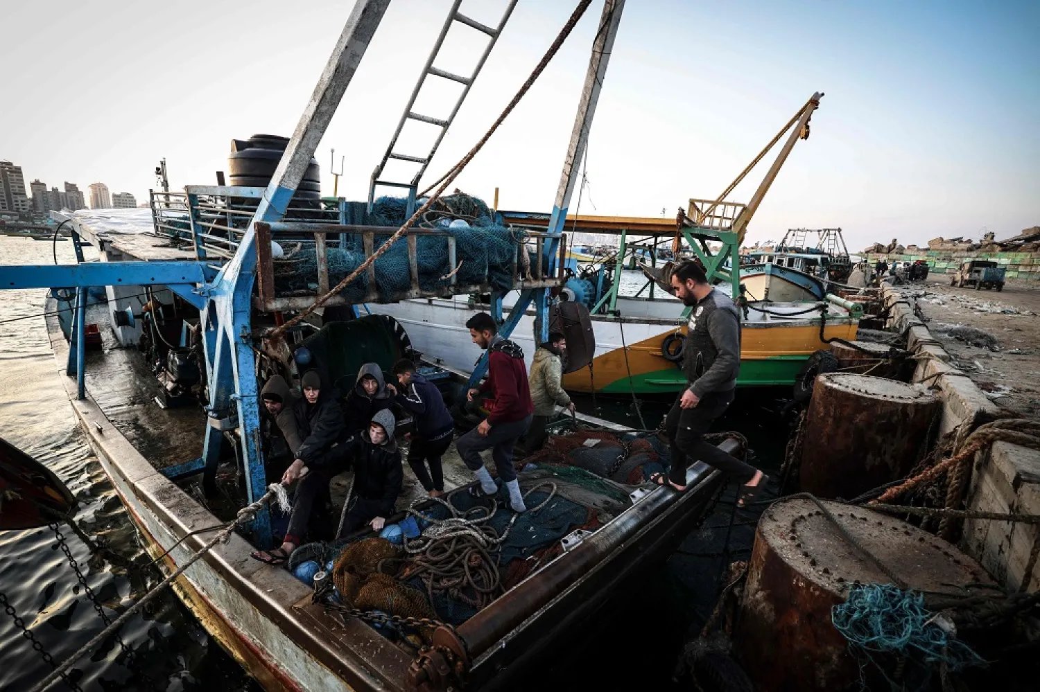 Palestinian fisherman Jihad al-Hissi and his sons work in their boat at the seaport in Gaza City on January 10, 2023. (AFP)
