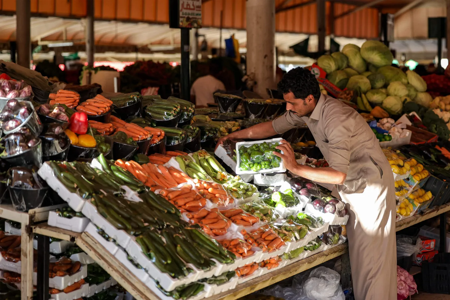 تاجر ينظم خضراوات في أحد أسواق الرياض (أ.ف.ب)