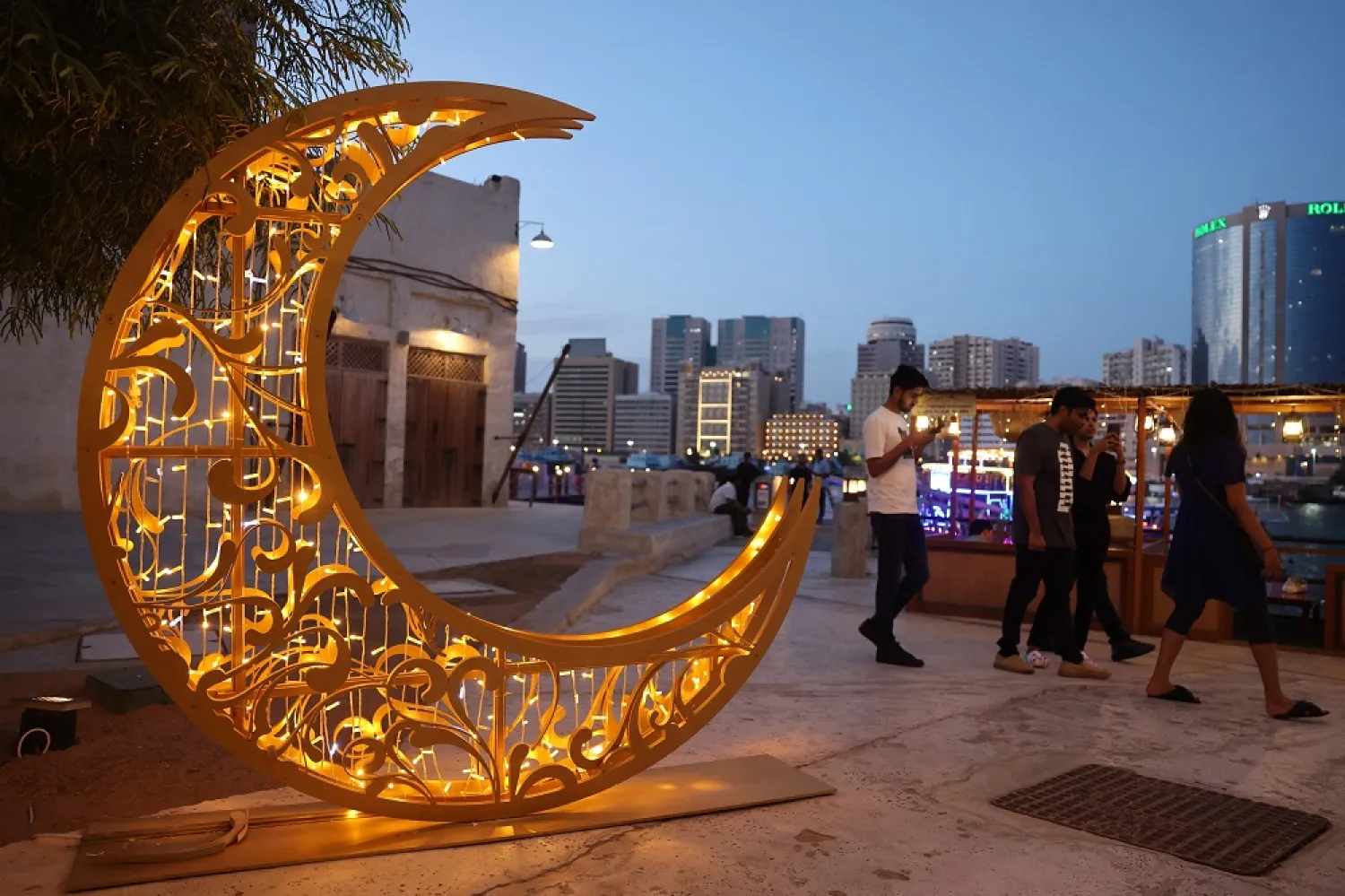 People walks past a crescent moon-shaped decoration during the Muslim holy fasting month of Ramadan, at Al-Seef in Dubai on March 26, 2023. (AFP)