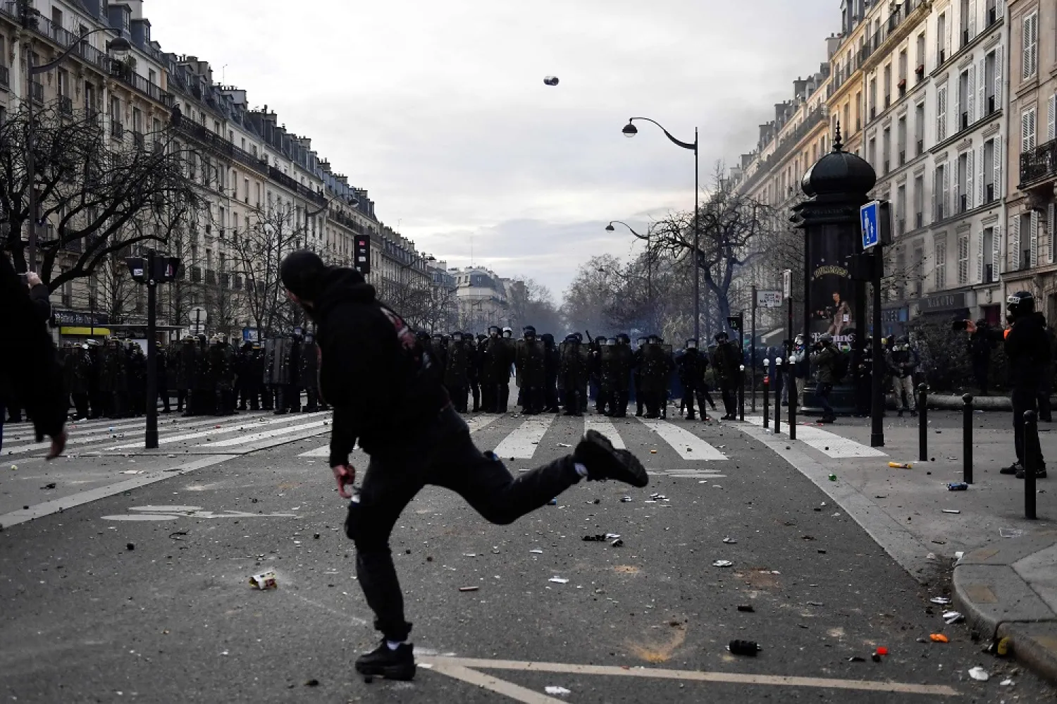 A protestor throws a canister towards security forces during a demonstration after the government pushed a pensions reform through parliament without a vote, using the article 49.3 of the constitution, in Paris on March 28, 2023. (AFP)