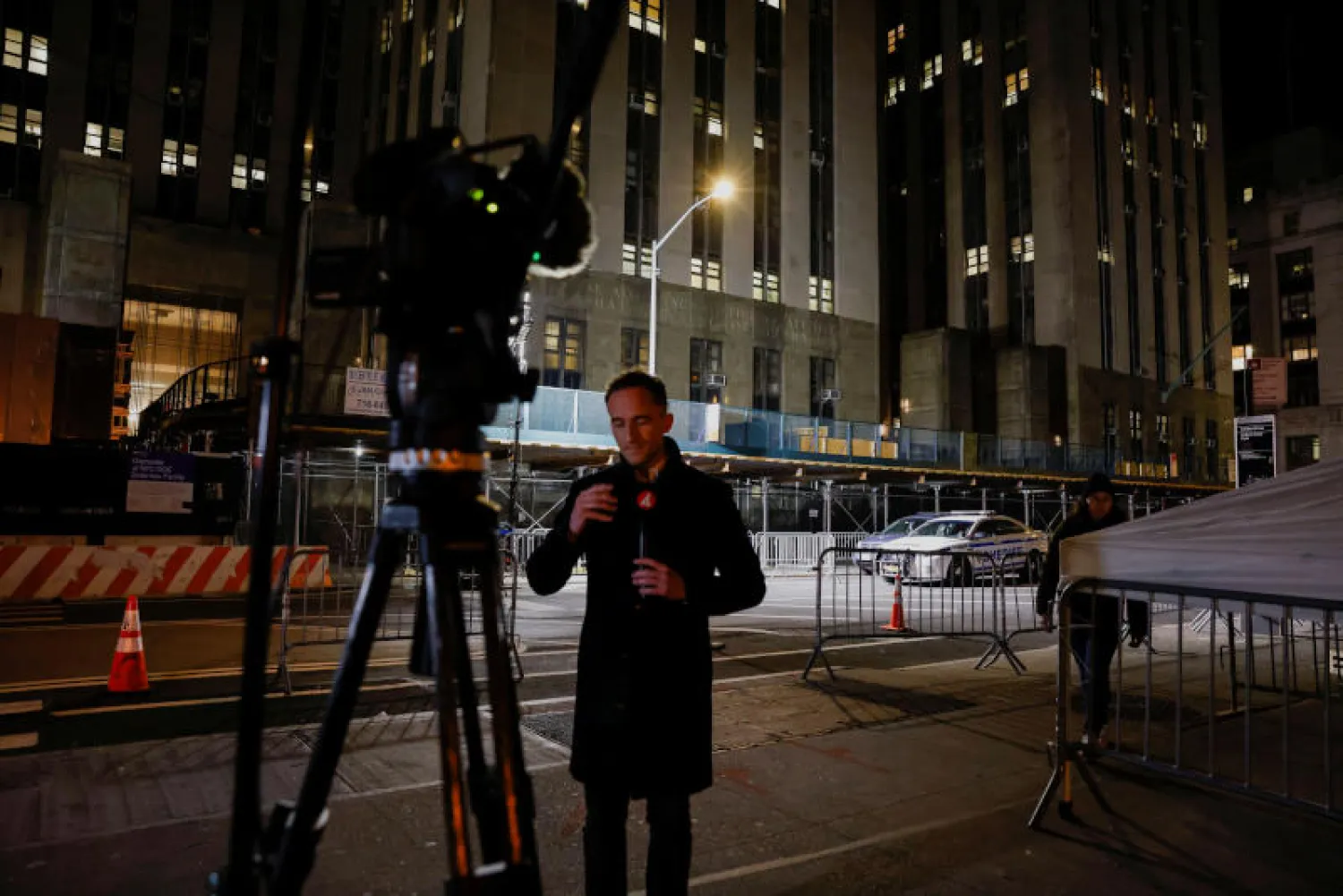 صحفي يقف أمام قاعة المحكمة في مانهاتن التي ستشهد توجيه الاتهامات لدونالد ترمب (رويترز)