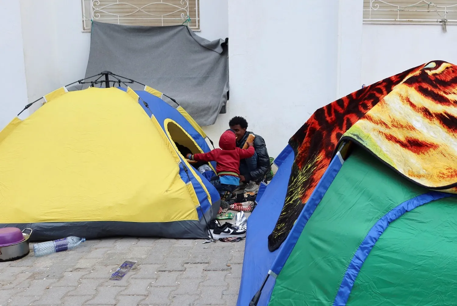 African migrants sit outside their tents at a temporary camp, near the headquarters of United Nations High Commissioner for Refugees (UNHCR), in Tunis, Tunisia March 22, 2023. (Reuters)